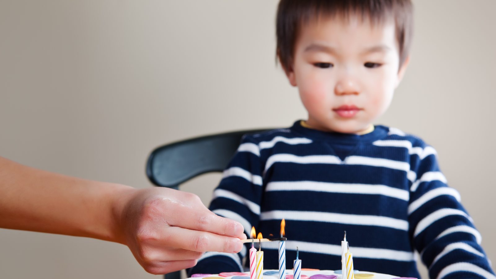 A young boy watching candles being lit on a birthday cake