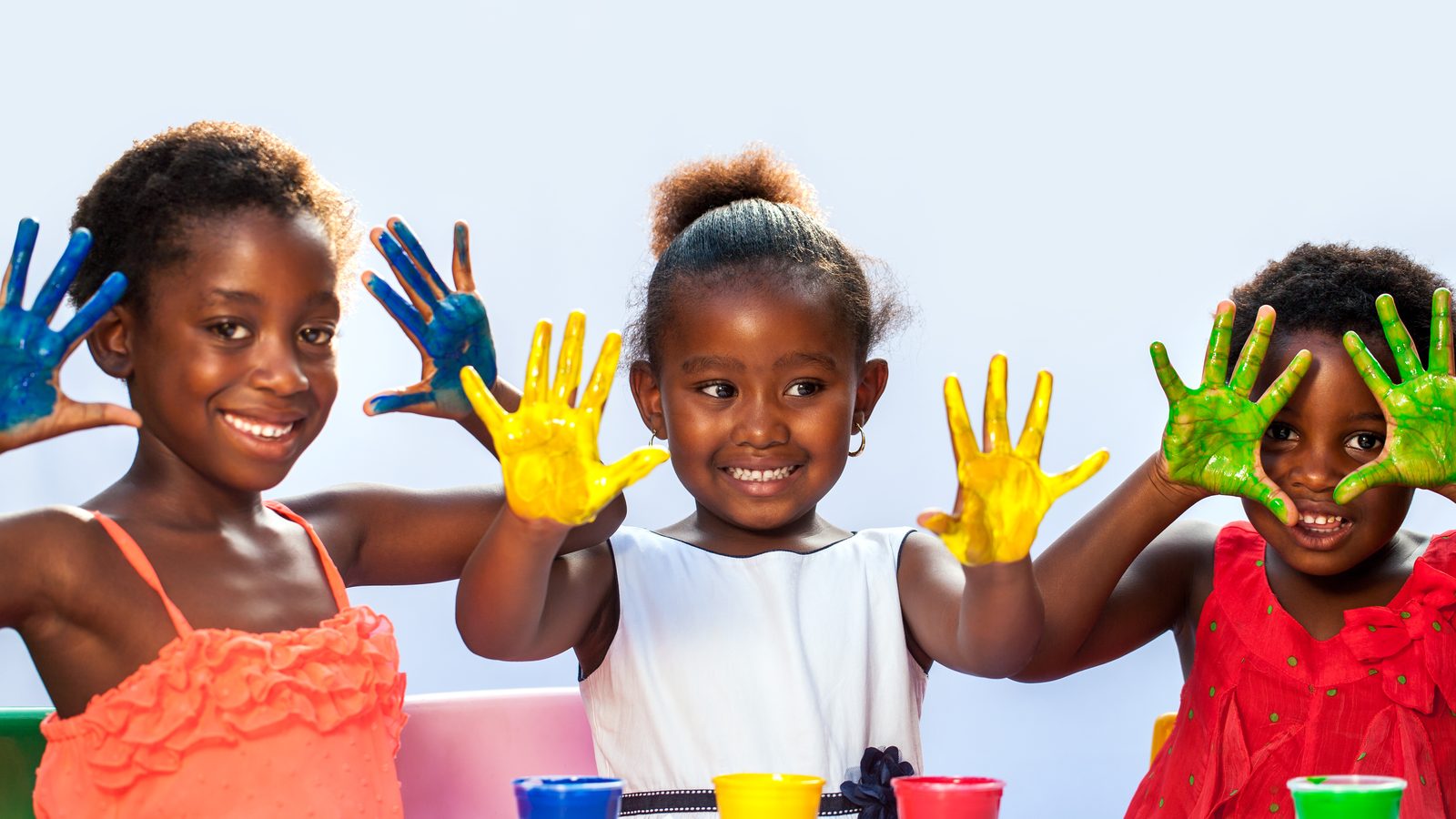 Three girls showing paint-covered hands