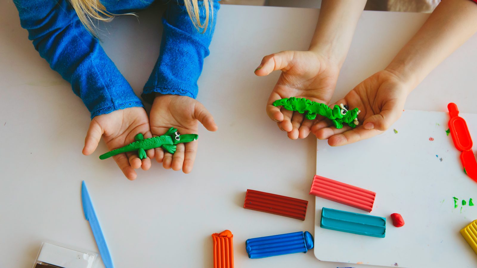 Hands rolling green play dough