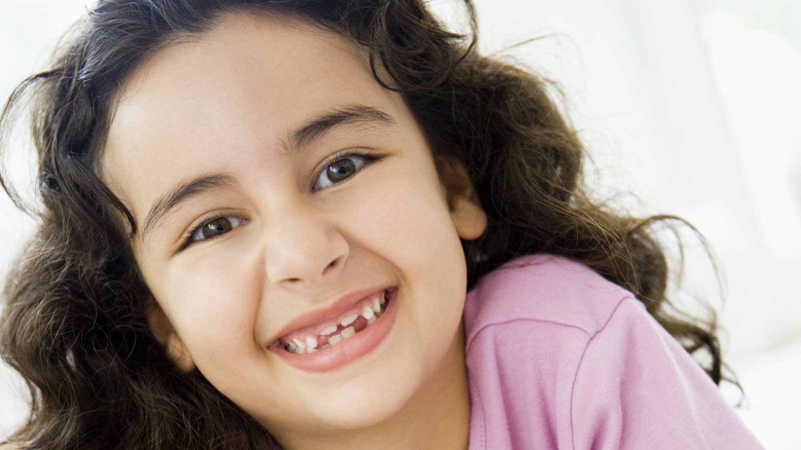 A smiling girl lying on the floor with a book