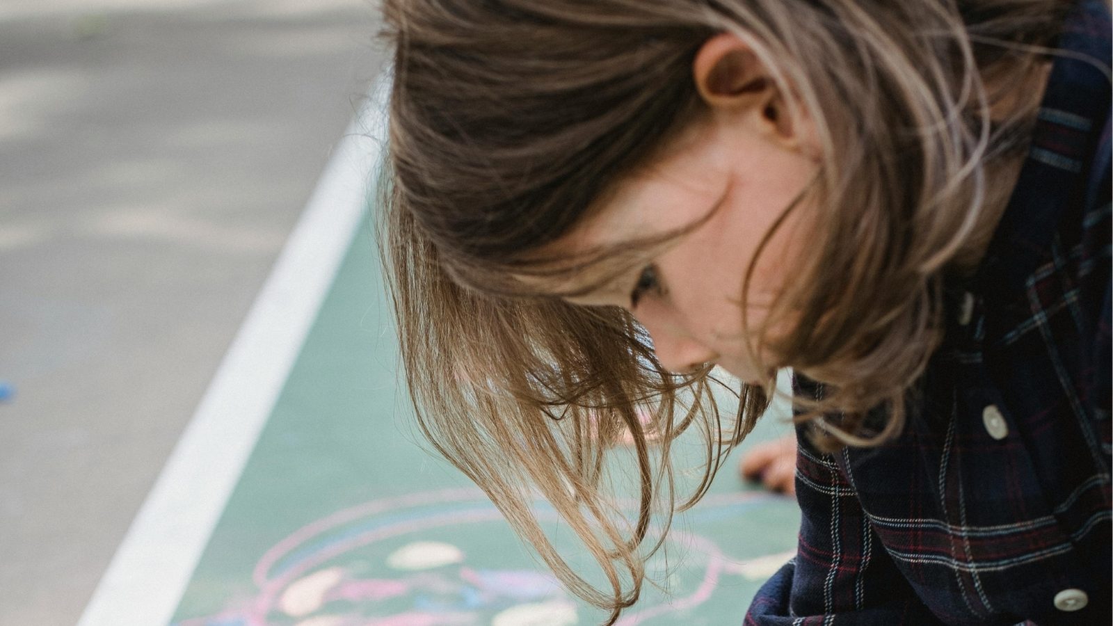A girl drawing with chalk on the playground