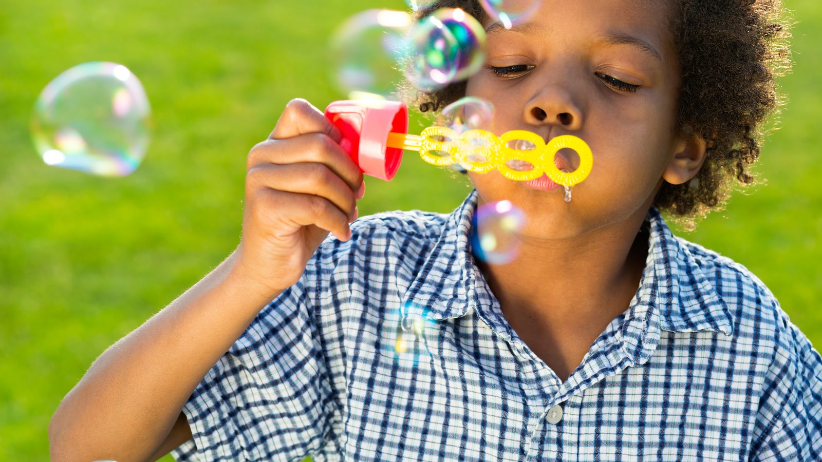 Boy blowing bubbles on the grass