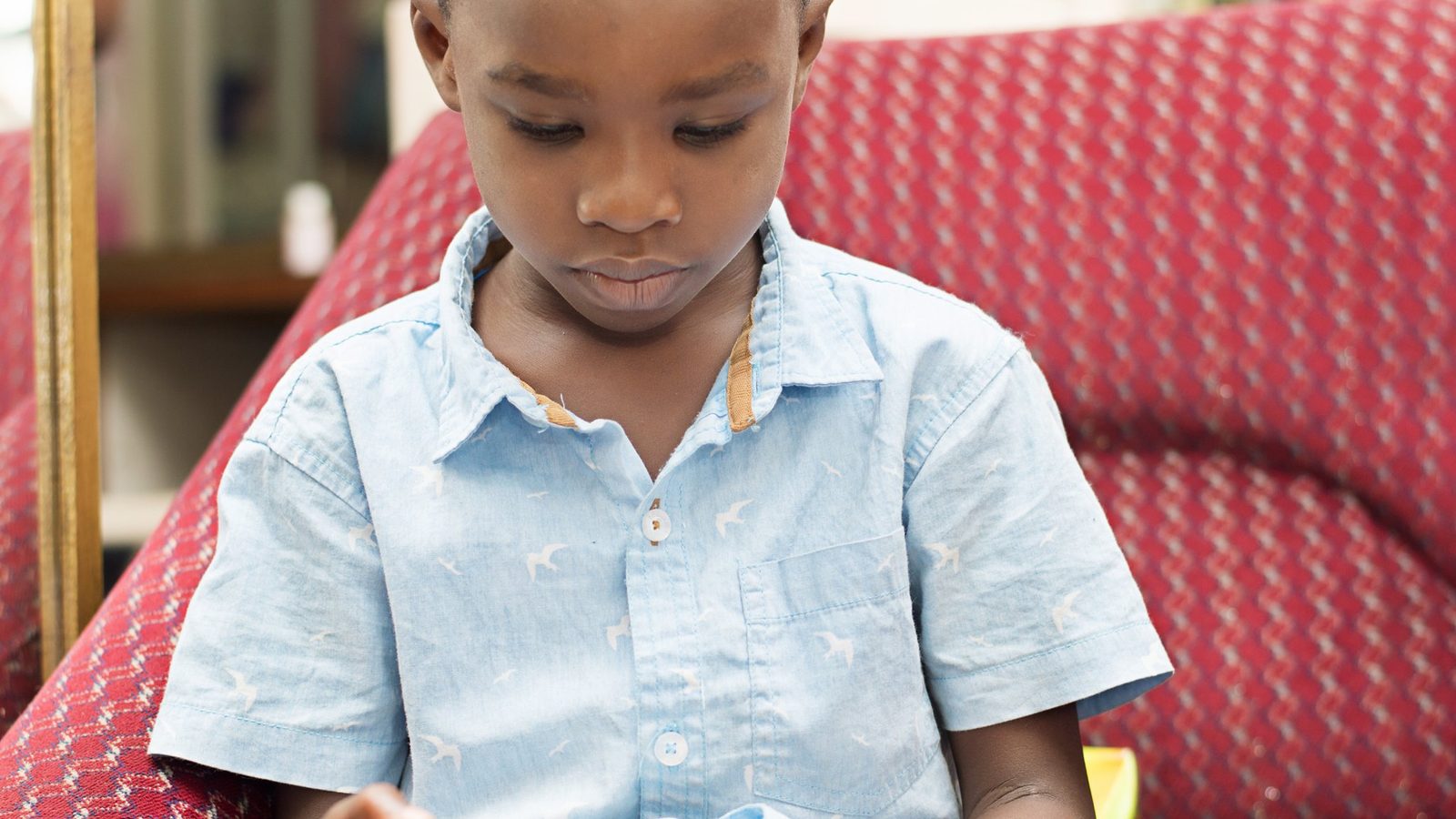 Boy reading in a red armchair