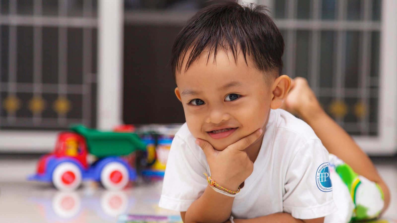 A smiling boy playing with a toy truck