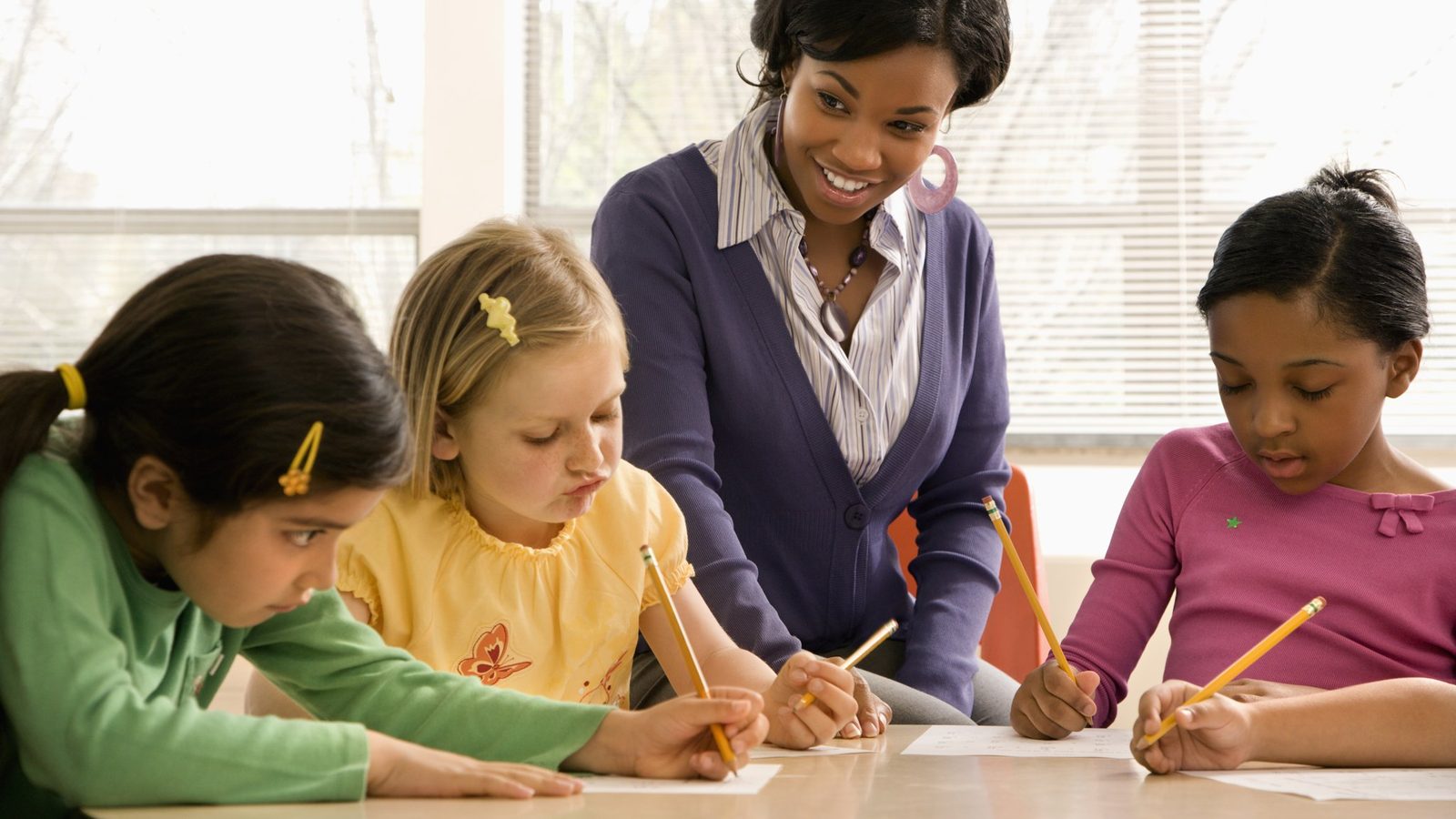 A teacher helping children with their writing