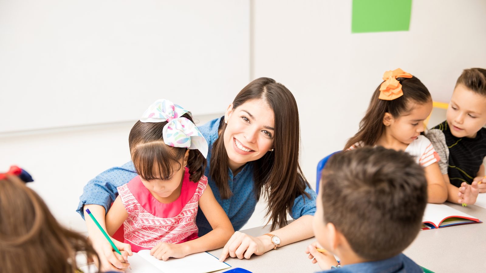 A teacher and children at a classroom table