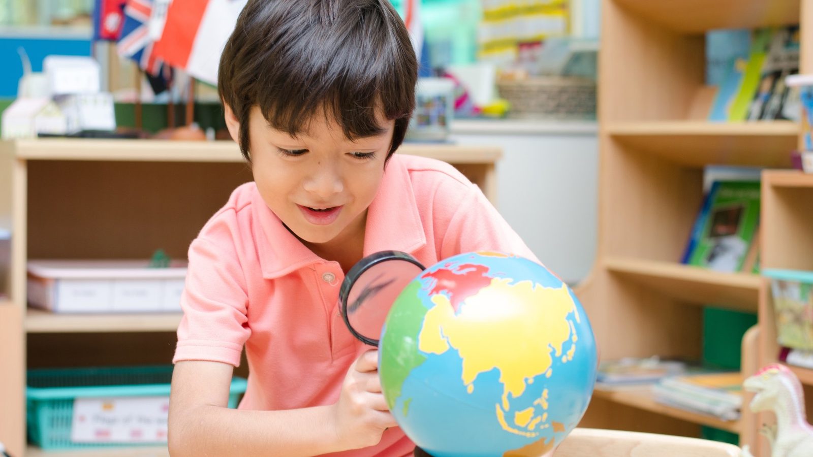 A boy looking at a globe in a classroom