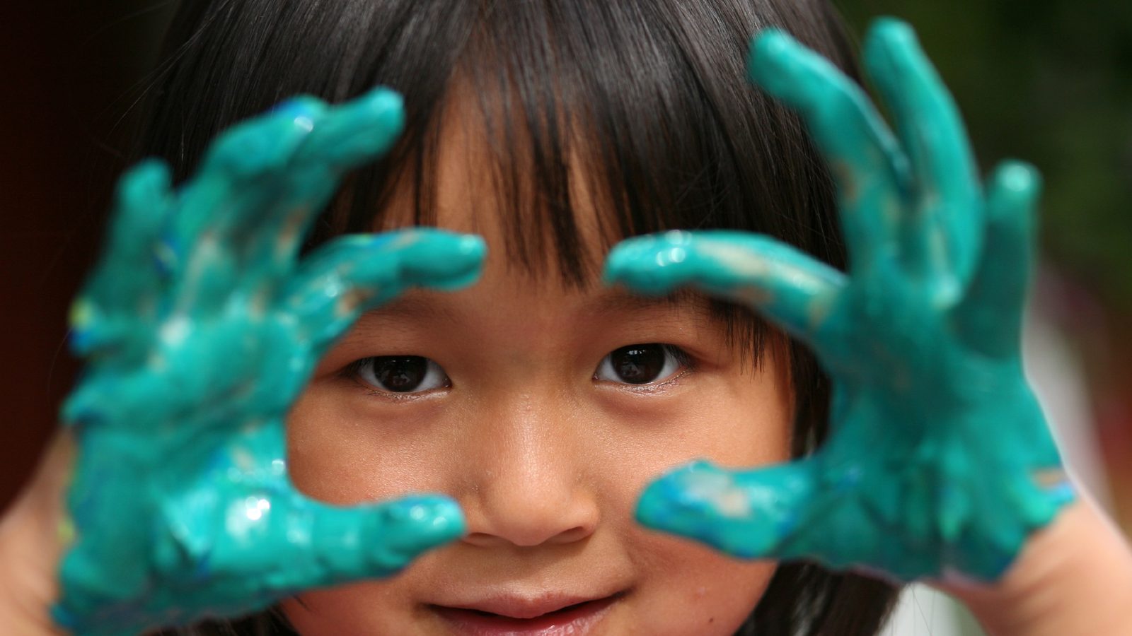 A child holding up paint-covered hands