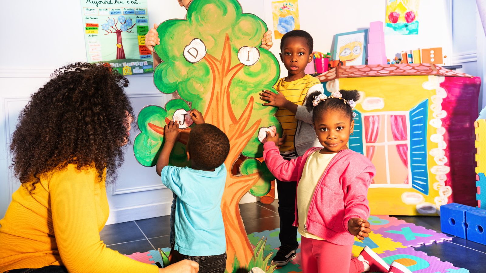 Children painting a mural with their teacher