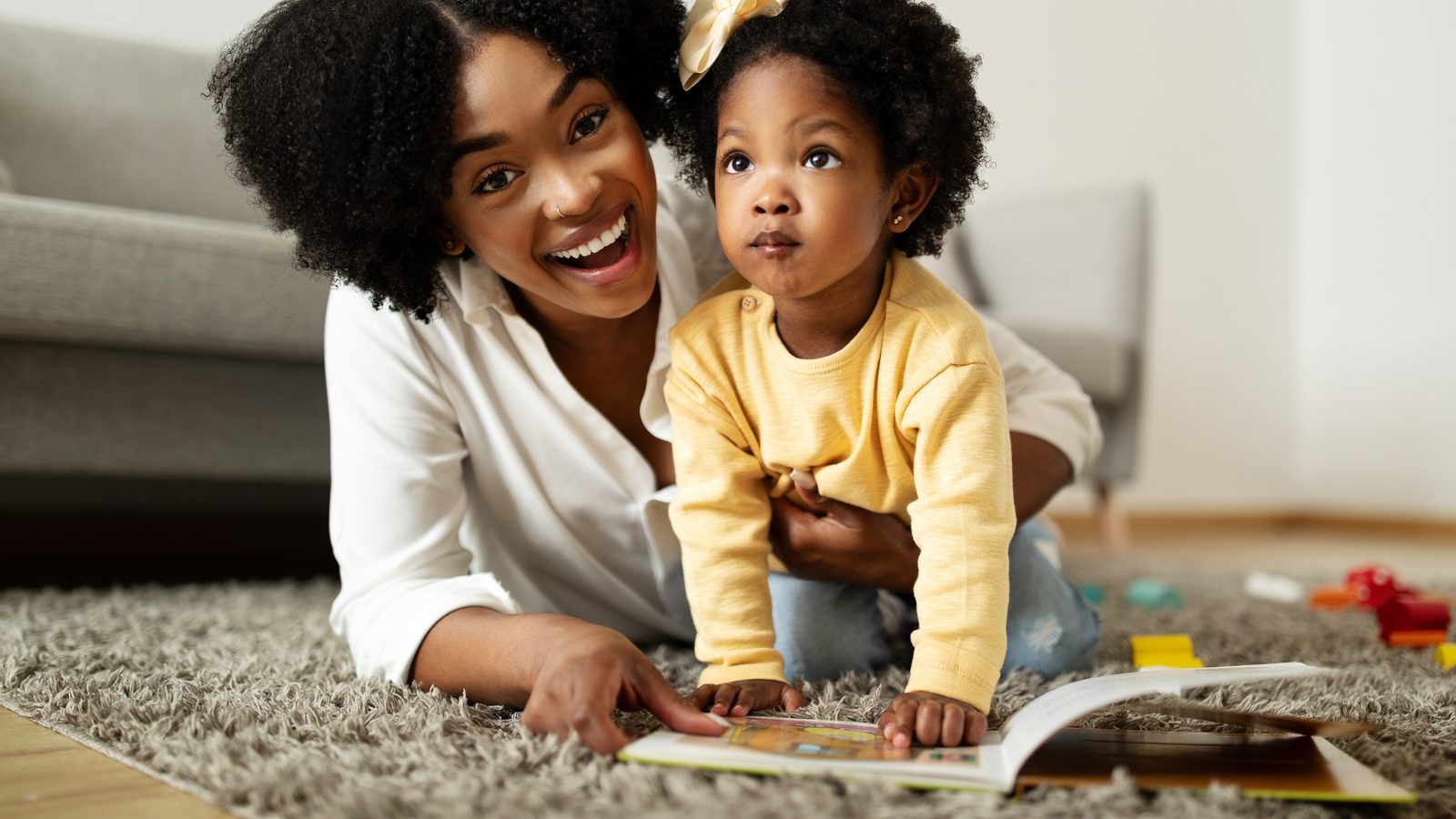A mother and toddler reading together on the floor