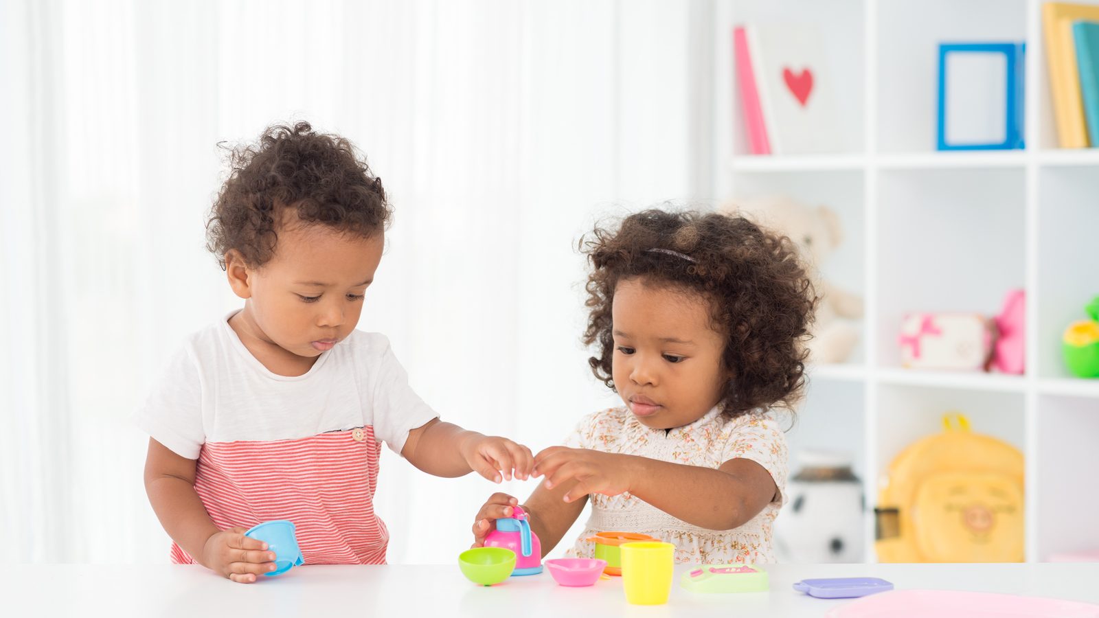 Two toddlers playing with toys at a table