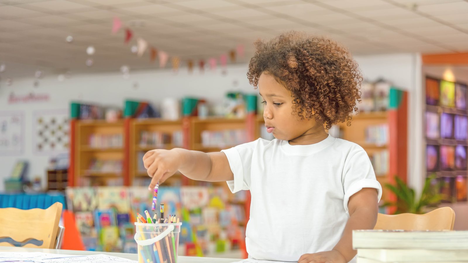 A girl painting at a table in a classroom