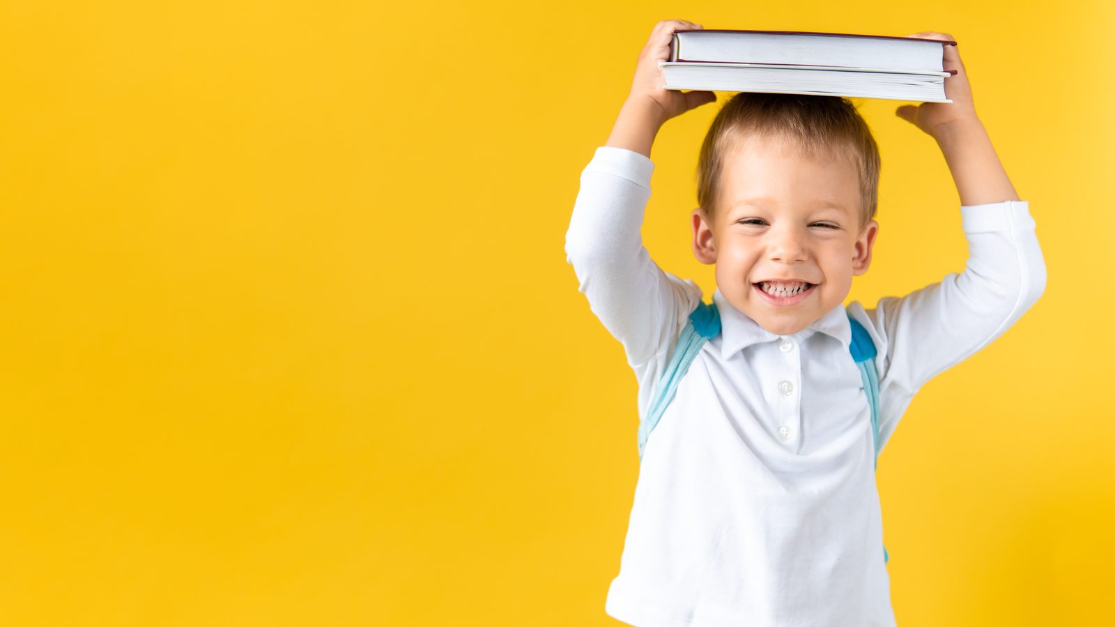 A playful boy balancing books on his head