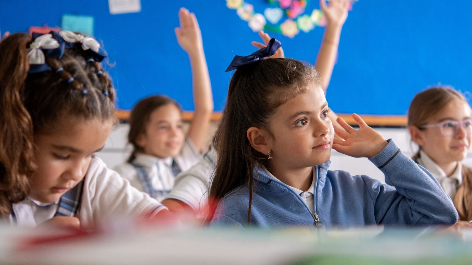 Children raising their hands in class