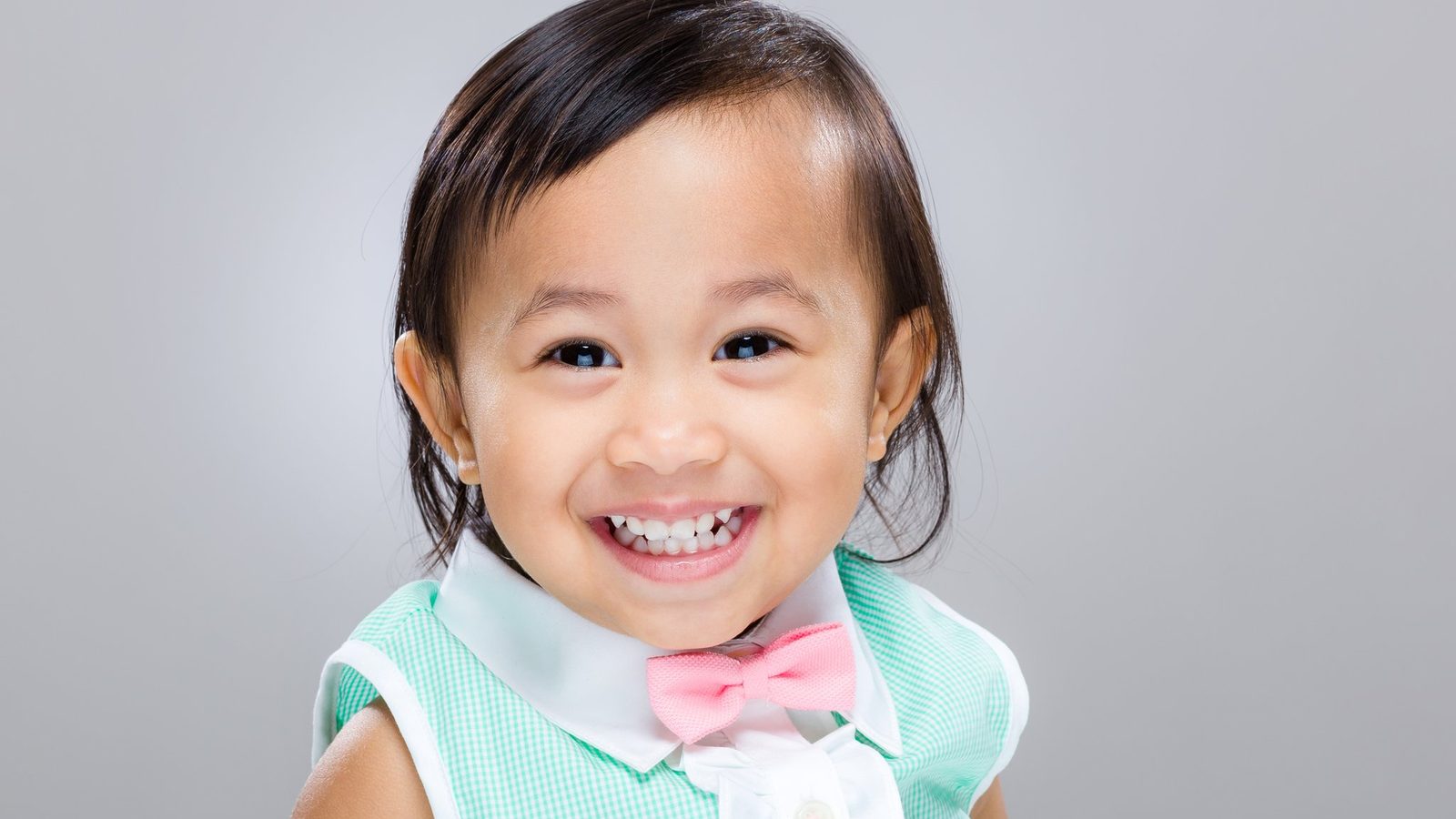 A smiling young girl in a teal top