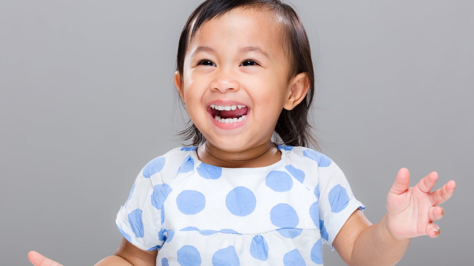 A laughing young girl in a polka-dot top