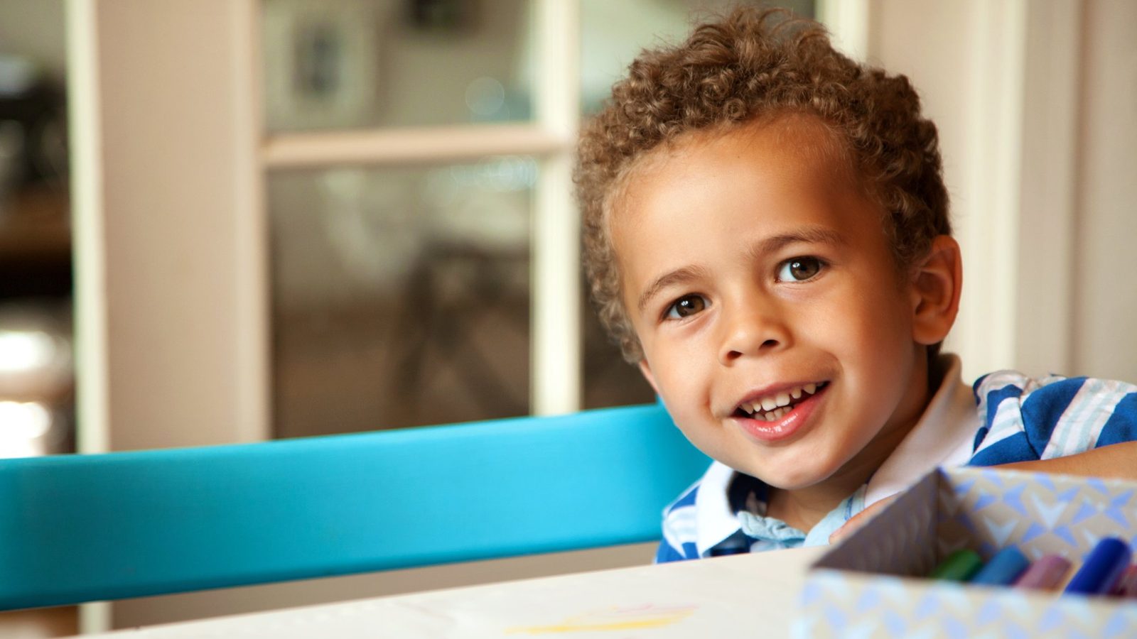 A smiling boy at a classroom table