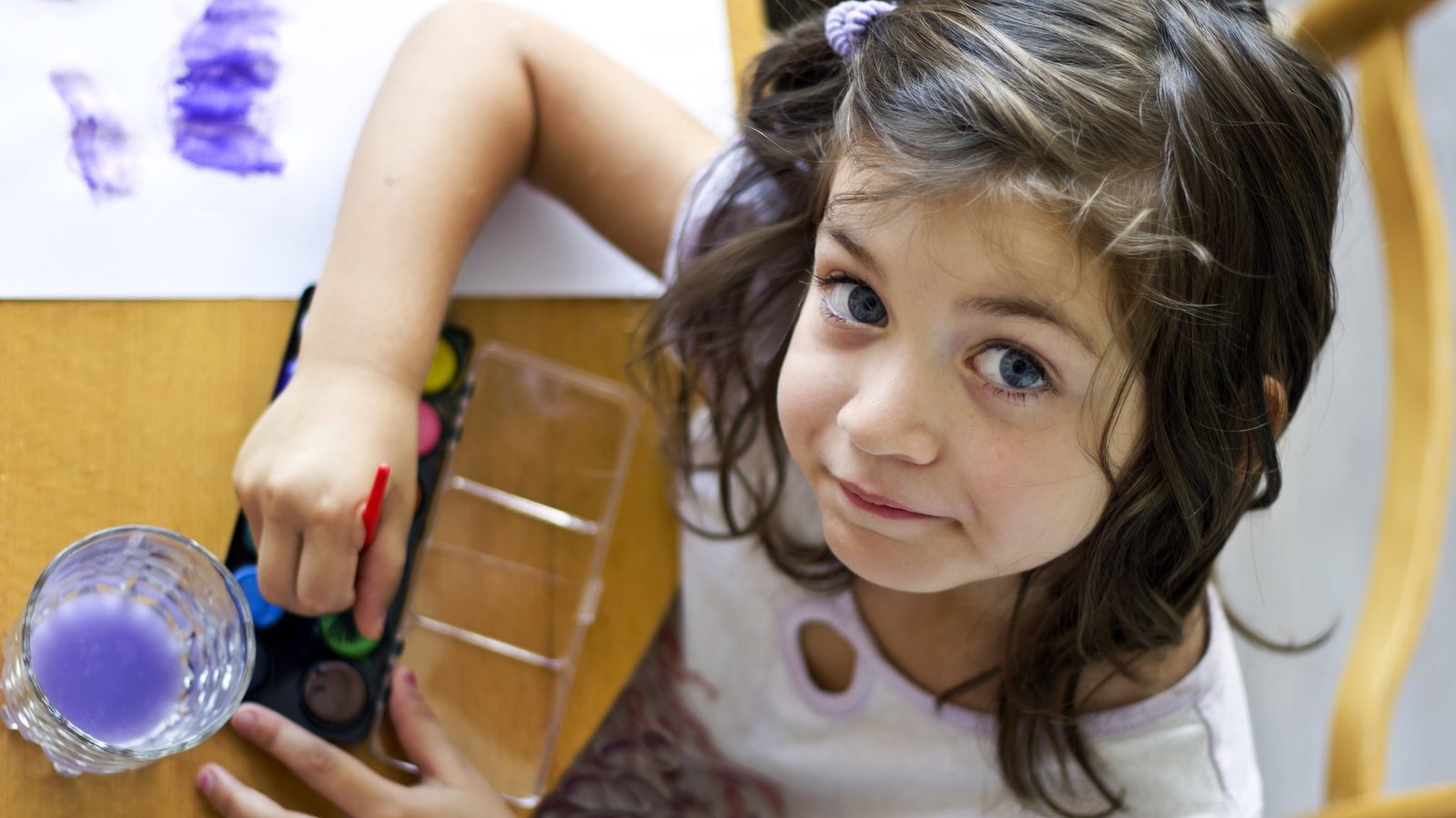 A smiling girl doing a craft activity at a table