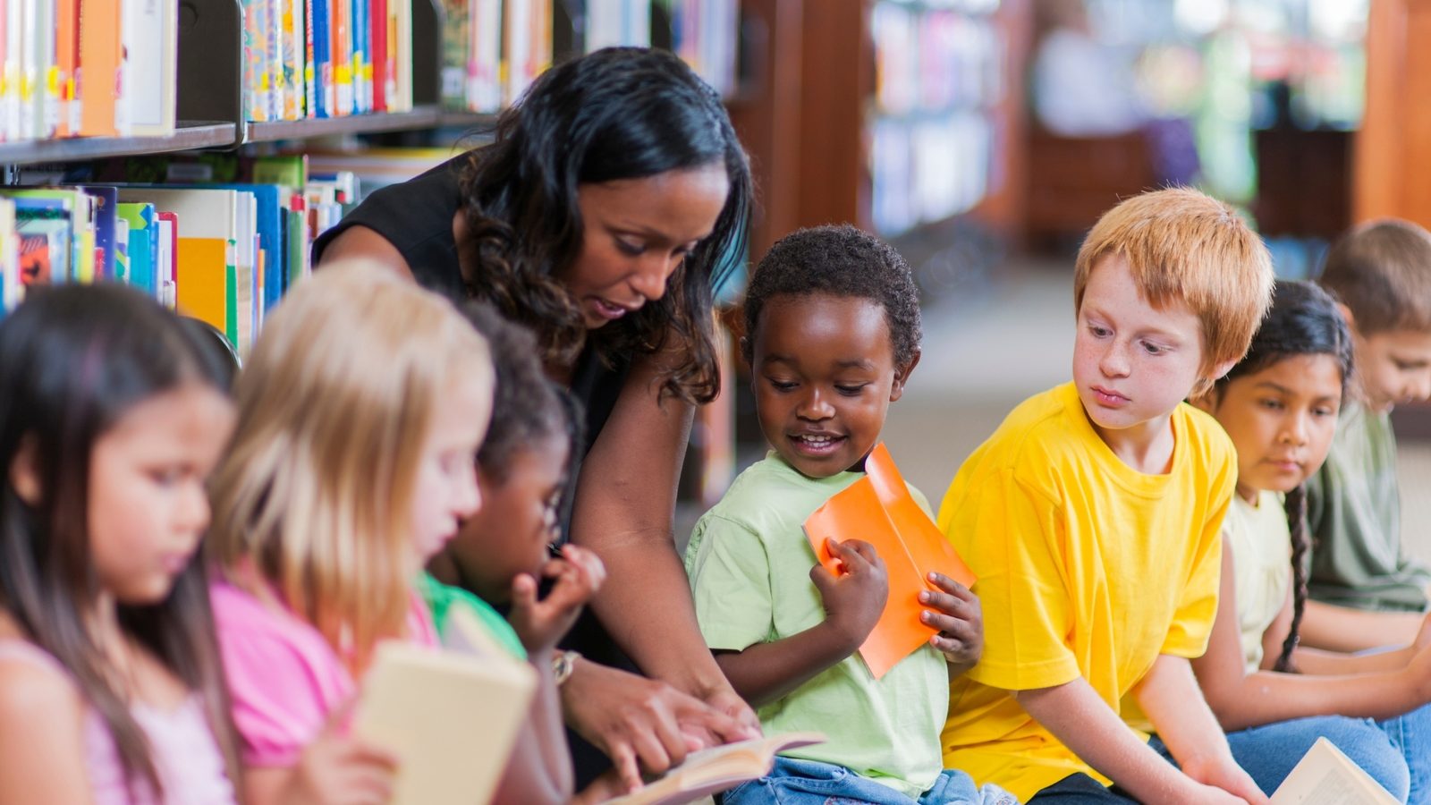 A teacher reading with a diverse group of preschool children