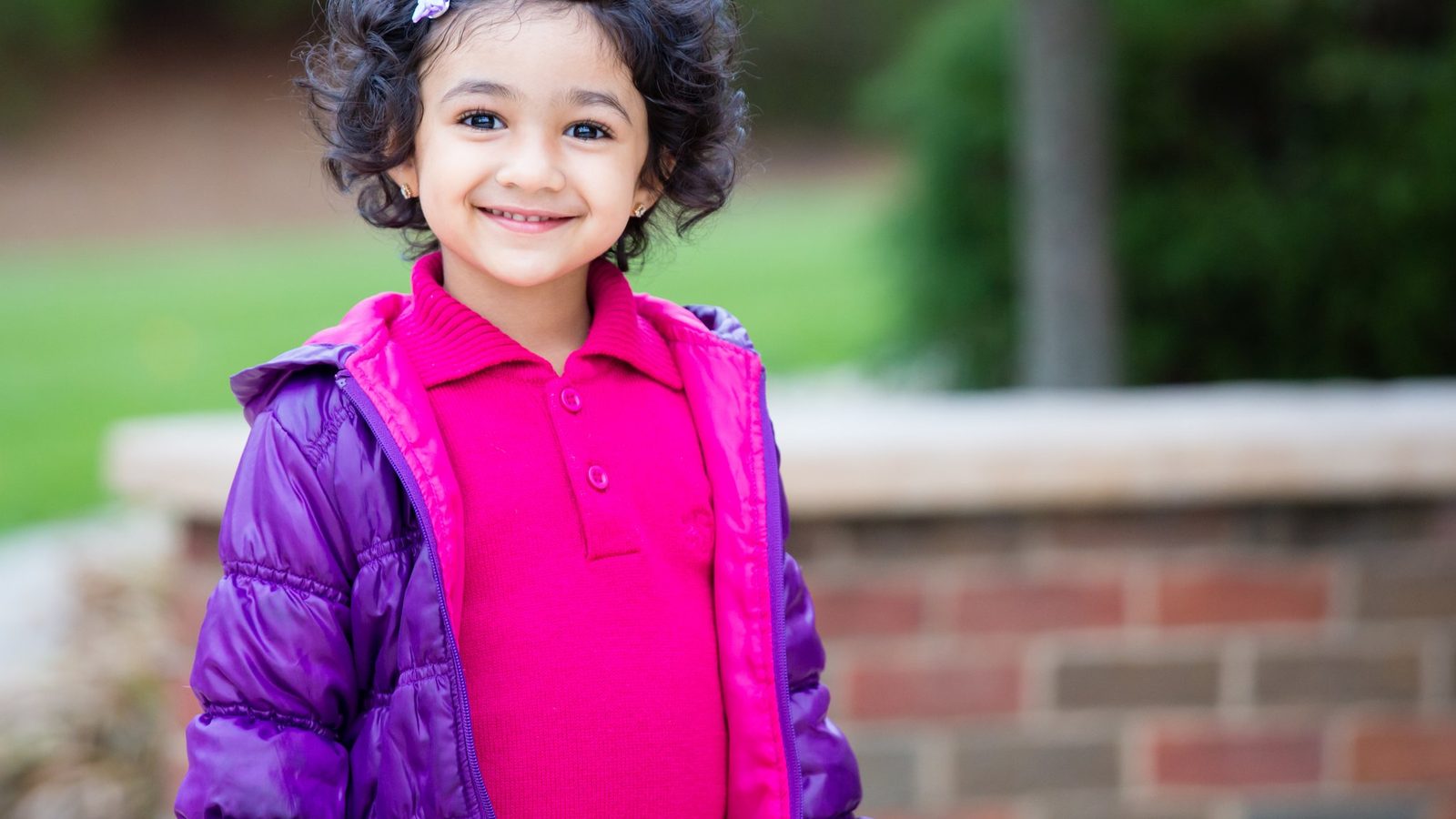 A smiling girl in a pink jacket outdoors