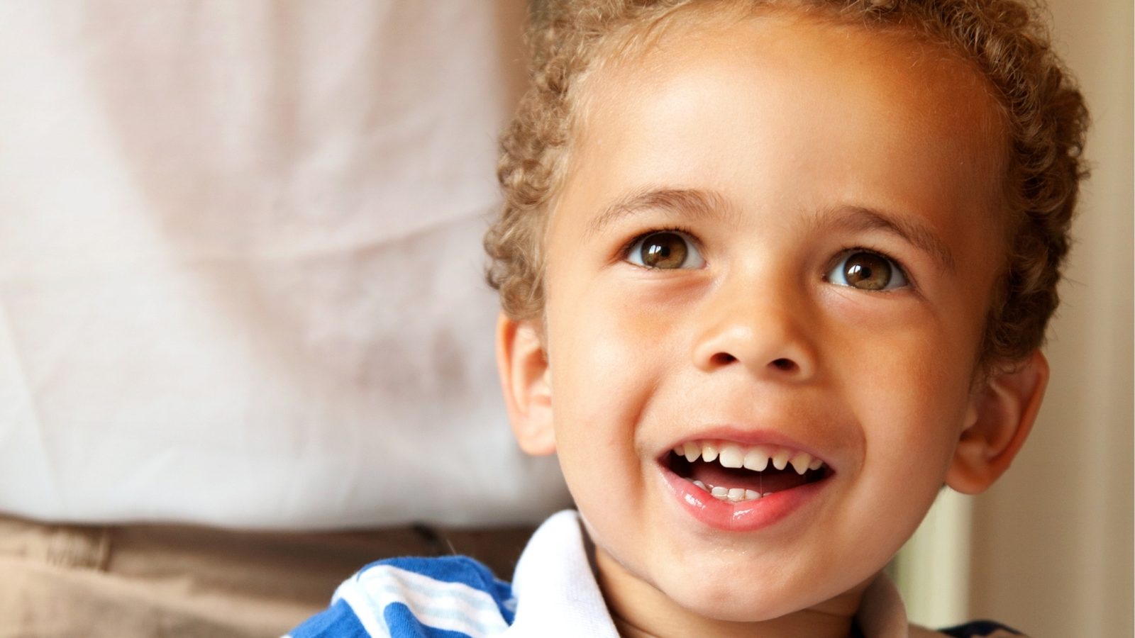 A smiling boy drawing at a preschool table