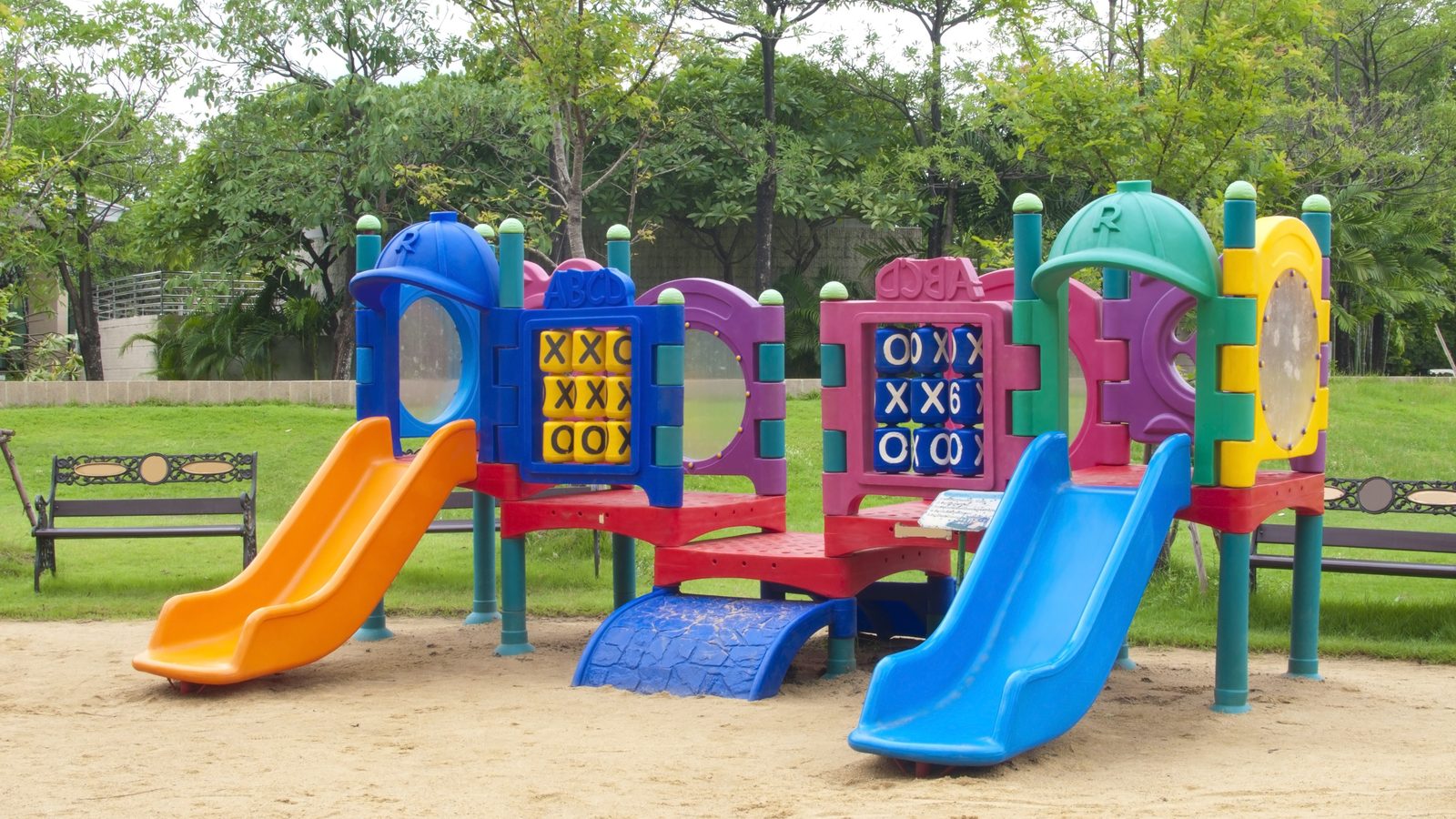 Empty playground with colourful slides among trees