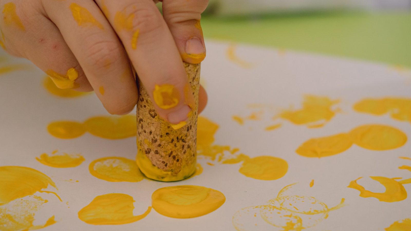 Hand dabbing yellow paint onto paper