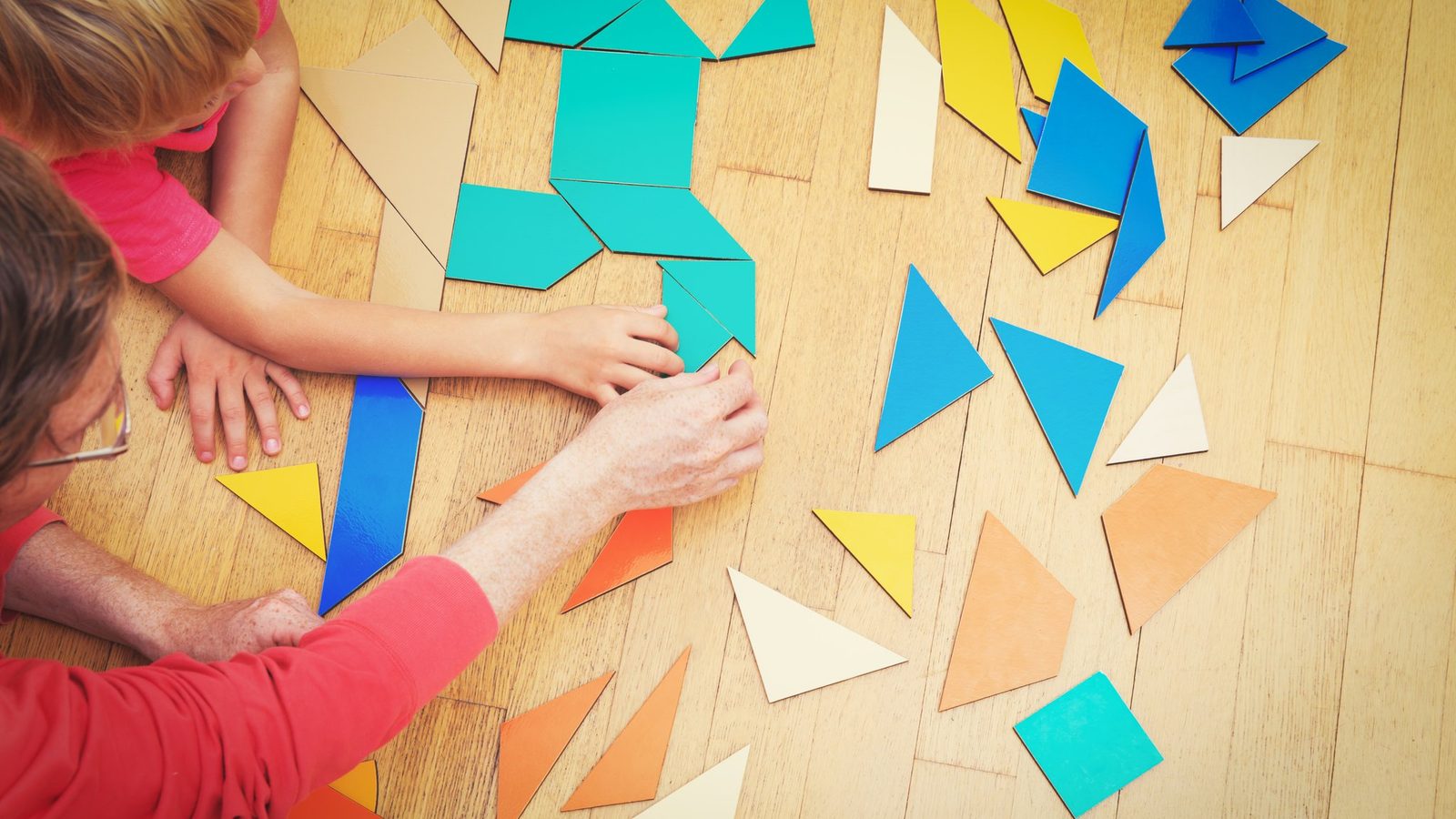 Hands arranging colourful paper shapes