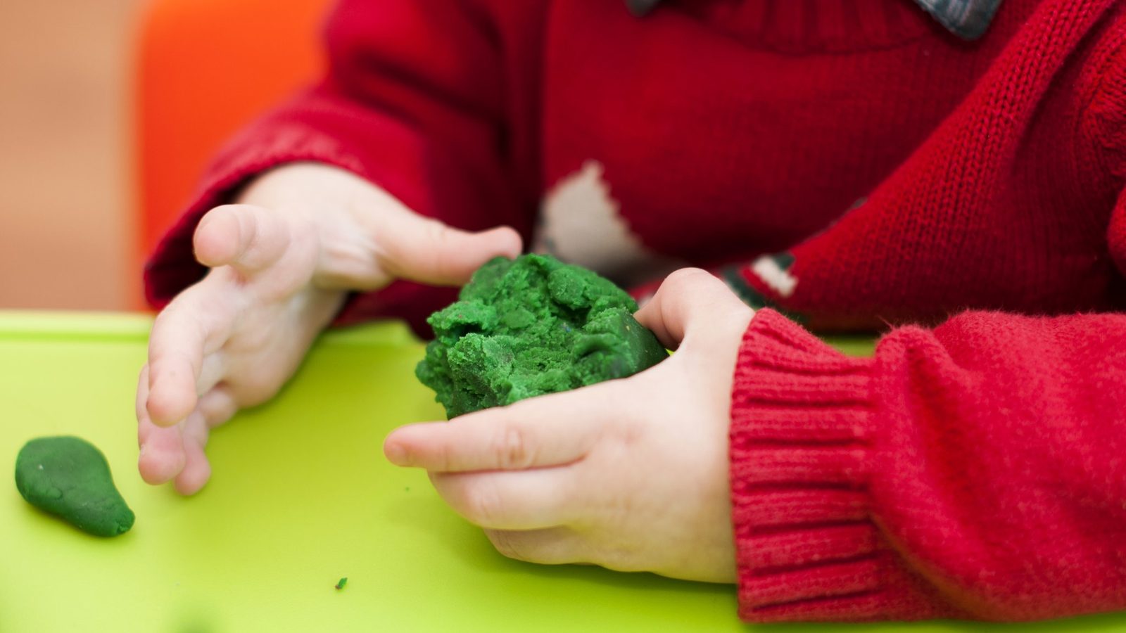 Hands shaping green play dough