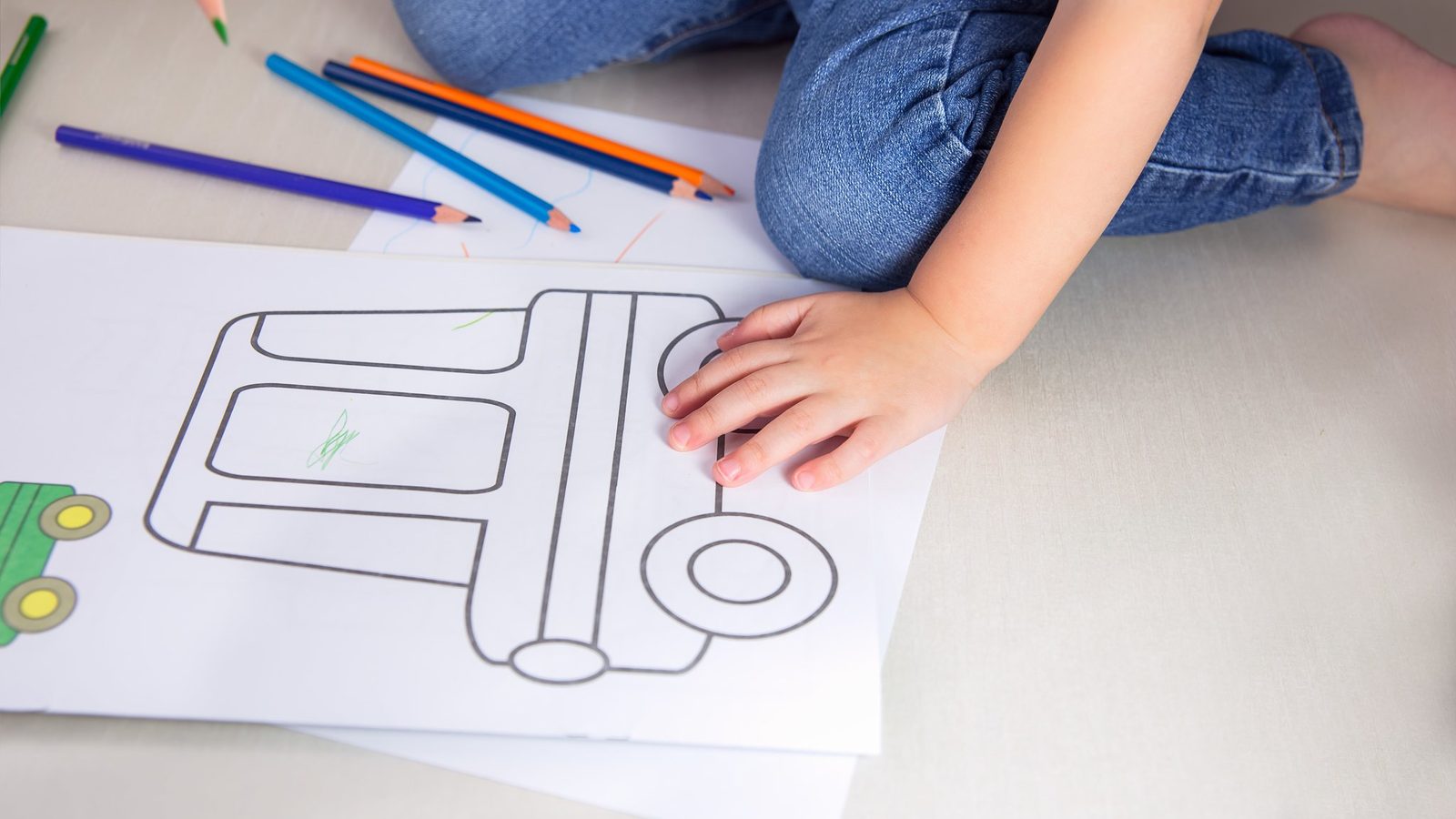 Hands colouring an outline of a truck