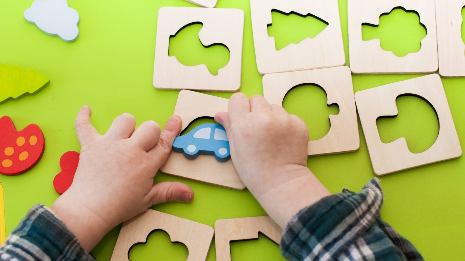 Hands fitting pieces into a wooden puzzle